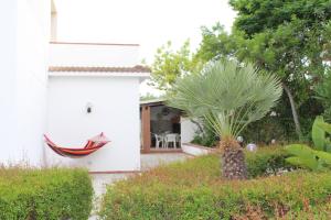 a white house with a hammock and a palm tree at Villa Paola Holidays in Sciacca