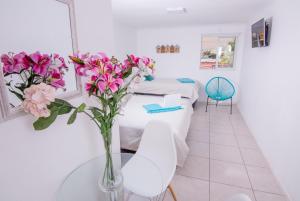 Cette chambre comprend un lit et un vase de fleurs sur une table. dans l'établissement Playa Hotel Stay Work & Play Cavancha, à Iquique