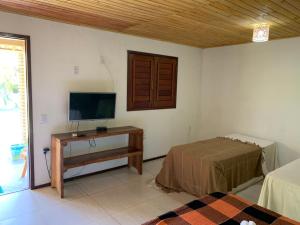 a room with a tv and a table with a bed at Pousada e Restaurante Encanto das Águas in São Miguel dos Milagres