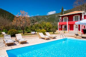 een zwembad met stoelen en een huis bij Red Villa in Nydri
