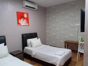 a hotel room with two beds and a desk at Hotel Kamelia in Kepala Batas