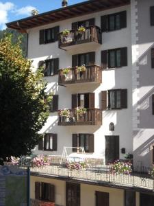 un edificio blanco con balcones y flores. en Appartamenti Donini Marco, en Molveno