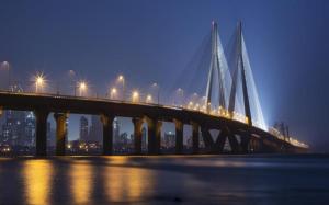 a large bridge over the water at night at Hotel Alfa International in Mumbai