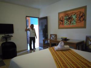 un hombre de pie en una habitación de hotel con una cama en Buenos Días Guest House, en Puerto Morelos