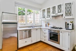 eine Küche mit weißen Schränken und Geräten aus Edelstahl in der Unterkunft Gowan Brae Cottage in Katoomba + 11 Fotos