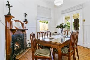 ein Esszimmer mit Tisch und Stühlen und einem Kamin in der Unterkunft Gowan Brae Cottage in Katoomba