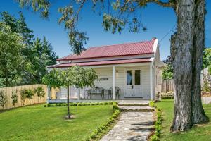 ein weißes Häuschen mit rotem Dach und einem Garten in der Unterkunft Gowan Brae Cottage in Katoomba