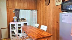 Cottage Yakusugi House في ياكوشيما: غرفة طعام مع طاولة خشبية وكراسي بيضاء