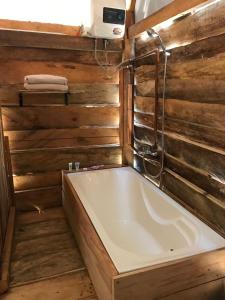 uma banheira na casa de banho com paredes de madeira em Chappi Mountains Bungalows em Da Ðeum (2)