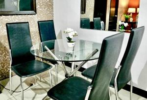 a glass table with green chairs in a dining room at Super Cute Hampton Suites in Imus