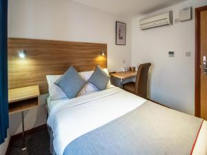 a hotel room with a large bed and a desk at OYO Arinza Hotel, London Ilford in Ilford