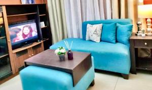 a living room with a blue couch and a tv at Super Cute Hampton Suites in Imus