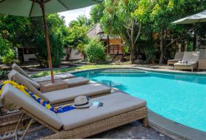 a swimming pool with lounge chairs and an umbrella at Si Pitung Village in Gili Air