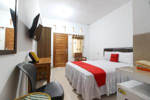 ein Schlafzimmer mit einem Bett, einem Schreibtisch und einem Fernseher in der Unterkunft RedDoorz Syariah at Kebun Raya Yogyakarta in Yogyakarta