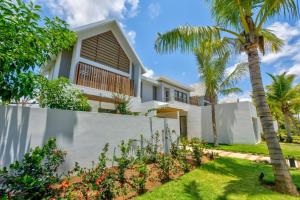 a house with a fence and palm trees at Mont Choisy Le Parc by Pam Golding in Grand-Baie