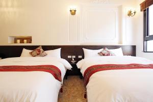 1 Schlafzimmer mit 2 Betten mit weißer Bettwäsche und einem Fenster in der Unterkunft Angel Wings Inn in Hualien