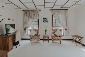 sala de estar con 2 sillas y TV en Cana Vineyard Guesthouse, en Paarl