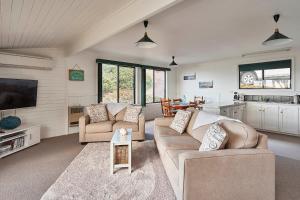 a living room with two couches and a tv at KINGFISHER COTTAGE Beachfront at the Binalong Bay in Binalong Bay