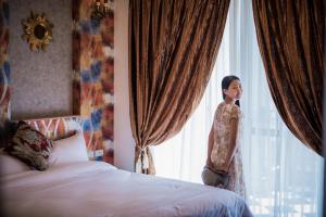 a woman standing in a bedroom looking out the window at Angel Wings Inn in Hualien City