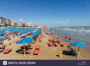 佩薩羅的住宿－il Gelsomino appartamento turistico，一片拥挤的海滩,上面摆放着椅子和遮阳伞,还有人