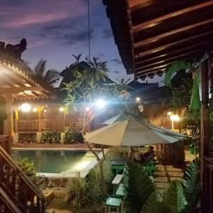 a patio with an umbrella and a pool at night at Green Paddy Hostel & Villa in Ubud