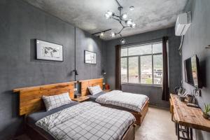 um quarto com 2 camas, uma mesa e uma janela em Hi Grey Hostel Xingping em Yangshuo