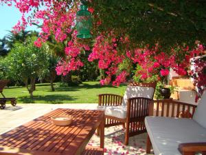 a patio with a table and two chairs and pink flowers at Quinta Verde Sintra - Casa de Campo in Sintra