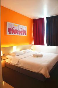 a bedroom with a large bed with orange walls at Hotel Jeti Tg Gemok in Padang Endau