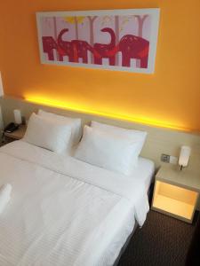 a bedroom with a white bed with a painting on the wall at Hotel Jeti Tg Gemok in Padang Endau