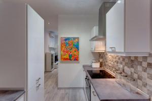 uma cozinha com armários brancos e uma pintura na parede em Modern Apartment 20 meters from the Promenade em Sliema