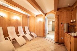a conference room with white chairs and a kitchen at Hotel San Martino in San Martino di Castrozza