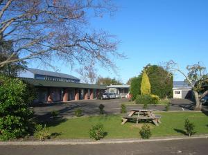 a picnic table in the grass in front of a building at Palmerston North Motel in Palmerston North