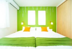 a bedroom with a large bed with green walls and windows at Park side Villa Izumi Komoike in Izumi