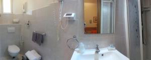 een badkamer met een wastafel, een spiegel en een toilet bij Hotel Europa in Albissola Marina