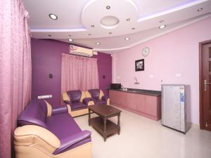 uma sala de espera com cadeiras roxas e uma mesa em Max Classic Serviced Apartment em Chennai