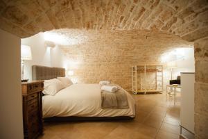 - une chambre avec un grand lit et un mur en briques dans l'établissement Pietre in Aria, à Noci
