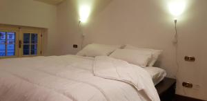 - un lit blanc dans une chambre avec deux lumières sur le mur dans l'établissement Attico con terrazza Villa Marianna, à Vérone