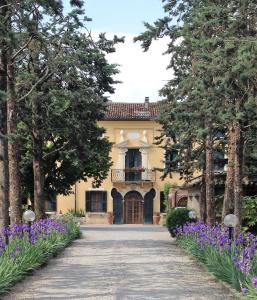 une grande maison jaune avec des fleurs et des arbres violets dans l'établissement Attico con terrazza Villa Marianna, à Vérone