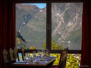 a table with wine glasses and a view of a mountain at Havila Hotel Geiranger in Geiranger