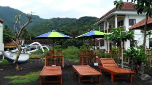 a group of chairs and umbrellas next to a house at Gula Juruh Beach Front in Amed
