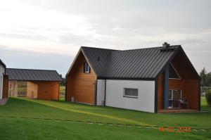 a house with a black roof and a white garage at Jaśminowy Sad in Mikołajki