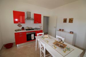 eine Küche mit einem weißen Tisch und roten Schränken in der Unterkunft Borgo Cenate in Santa Caterina di Nardò