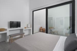 Un dormitorio con una cama y un televisor y una ventana. en Mea Terra Villas, en Lachania