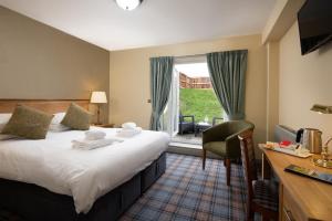 a hotel room with a bed and a desk and a window at The Bamburgh Castle Inn - The Inn Collection Group in Seahouses
