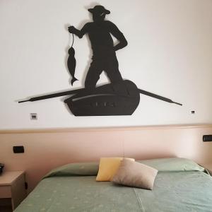 a silhouette of a man in a canoe on a wall above a bed at Hotel Fioroni in Bellagio