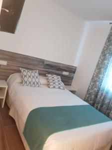 a bedroom with a large bed with a wooden headboard at Hostal Cabañas in Carboneras de Guadazaón