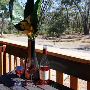 a table with two glasses of wine and a vase with flowers at Forest View in Creswick