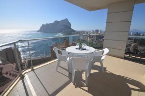 een witte tafel en stoelen op een balkon met uitzicht op de oceaan bij Apartamentos Entremares - Grupo Antonio Perles in Calpe
