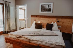 Schlafzimmer mit einem großen Bett mit einem Kopfteil aus Holz in der Unterkunft Landhaus Alpengruss in Kössen