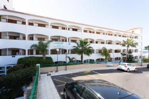 een groot wit gebouw met auto's geparkeerd op een parkeerplaats bij Apartment direkt am Meer in Costa Del Silencio